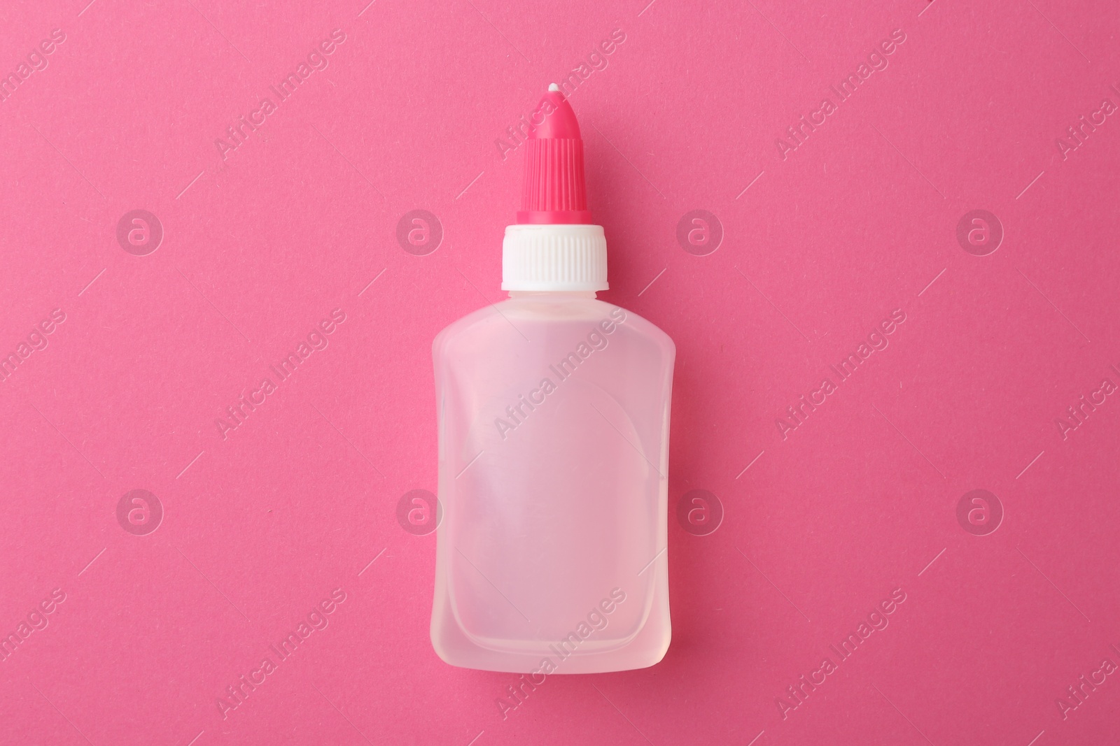 Photo of Bottle of glue on pink background, top view