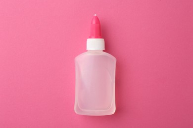 Bottle of glue on pink background, top view