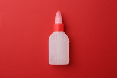 Photo of Bottle of glue on red background, top view