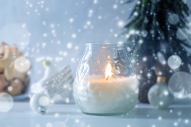 Image of Christmas composition with burning candle on white table, bokeh effect. Festive card