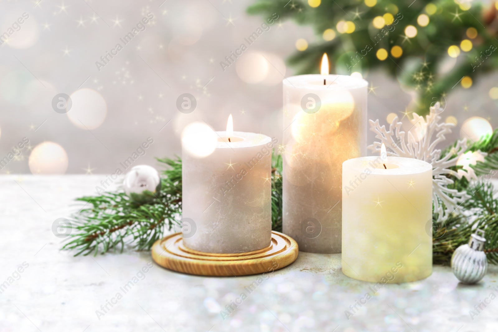 Image of Christmas composition with burning candles on white table, bokeh effect. Festive card