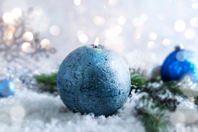 Image of Christmas composition with burning candle on snow, bokeh effect. Festive card