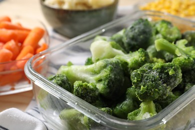 Photo of Frozen broccoli in glass container on table, closeup