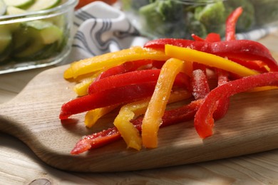 Photo of Slices of frozen bell peppers on wooden table, closeup