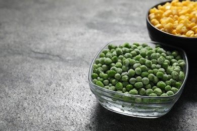 Photo of Frozen green peas and corn kernels on grey table, closeup. Space for text