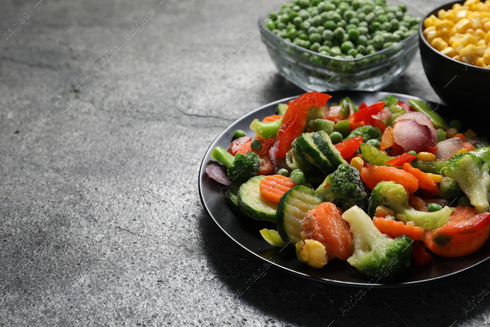 Photo of Different frozen vegetables on grey table, closeup. Space for text