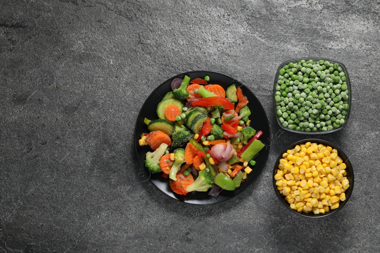 Photo of Different frozen vegetables on grey table, top view. Space for text