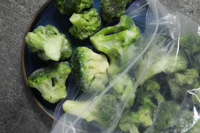 Photo of Frozen broccoli out of plastic bag on grey table, top view