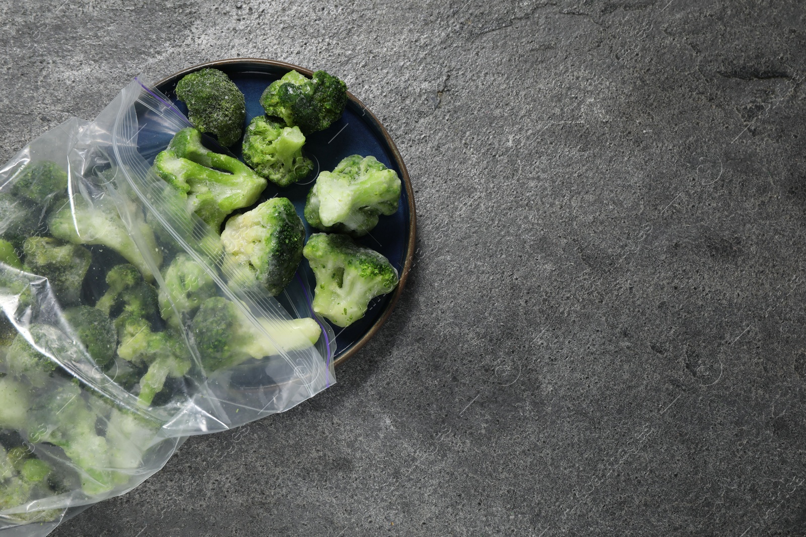 Photo of Frozen broccoli out of plastic bag on grey table, top view. Space for text