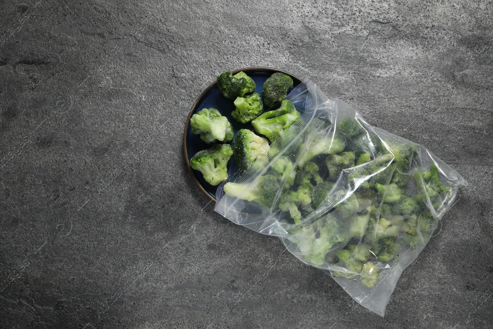 Photo of Frozen broccoli out of plastic bag on grey table, top view. Space for text