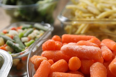 Photo of Different frozen vegetables in containers on table, closeup