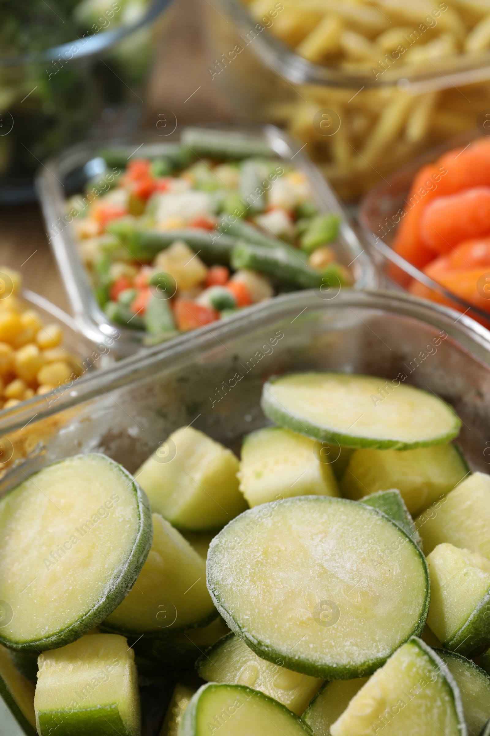 Photo of Different frozen vegetables in containers on table, closeup