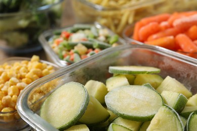 Photo of Different frozen vegetables in containers on table, closeup