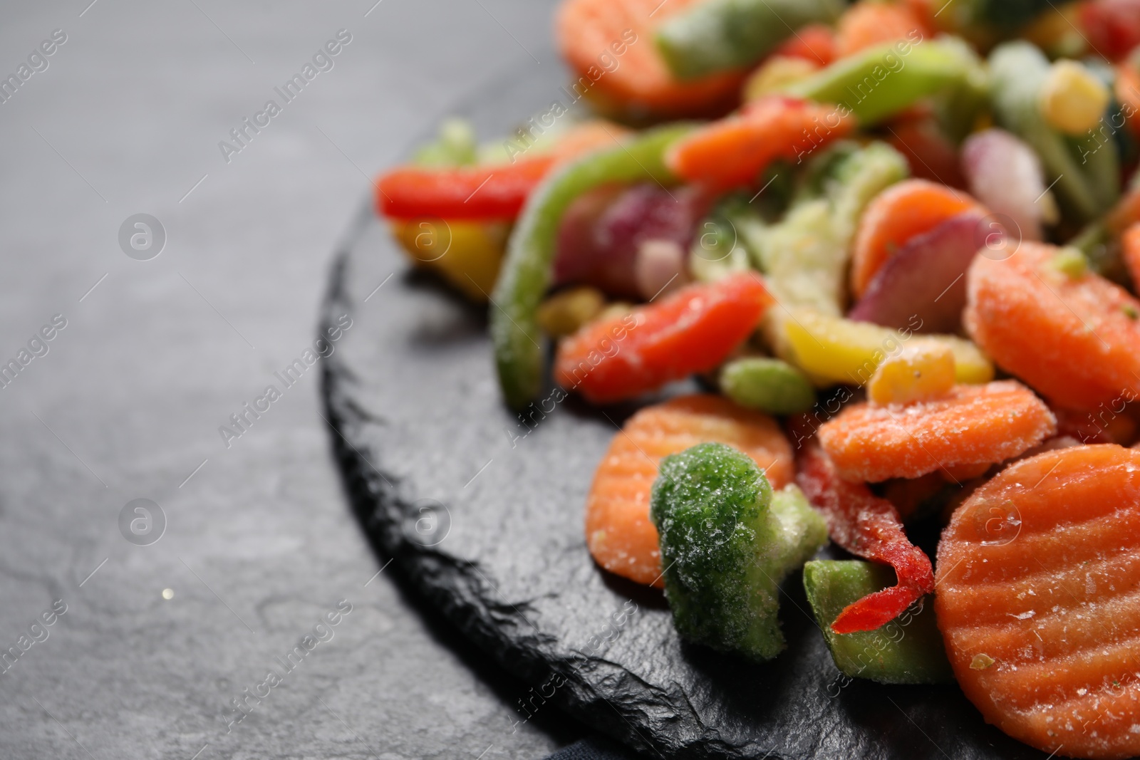 Photo of Mix of frozen vegetables on black table, closeup