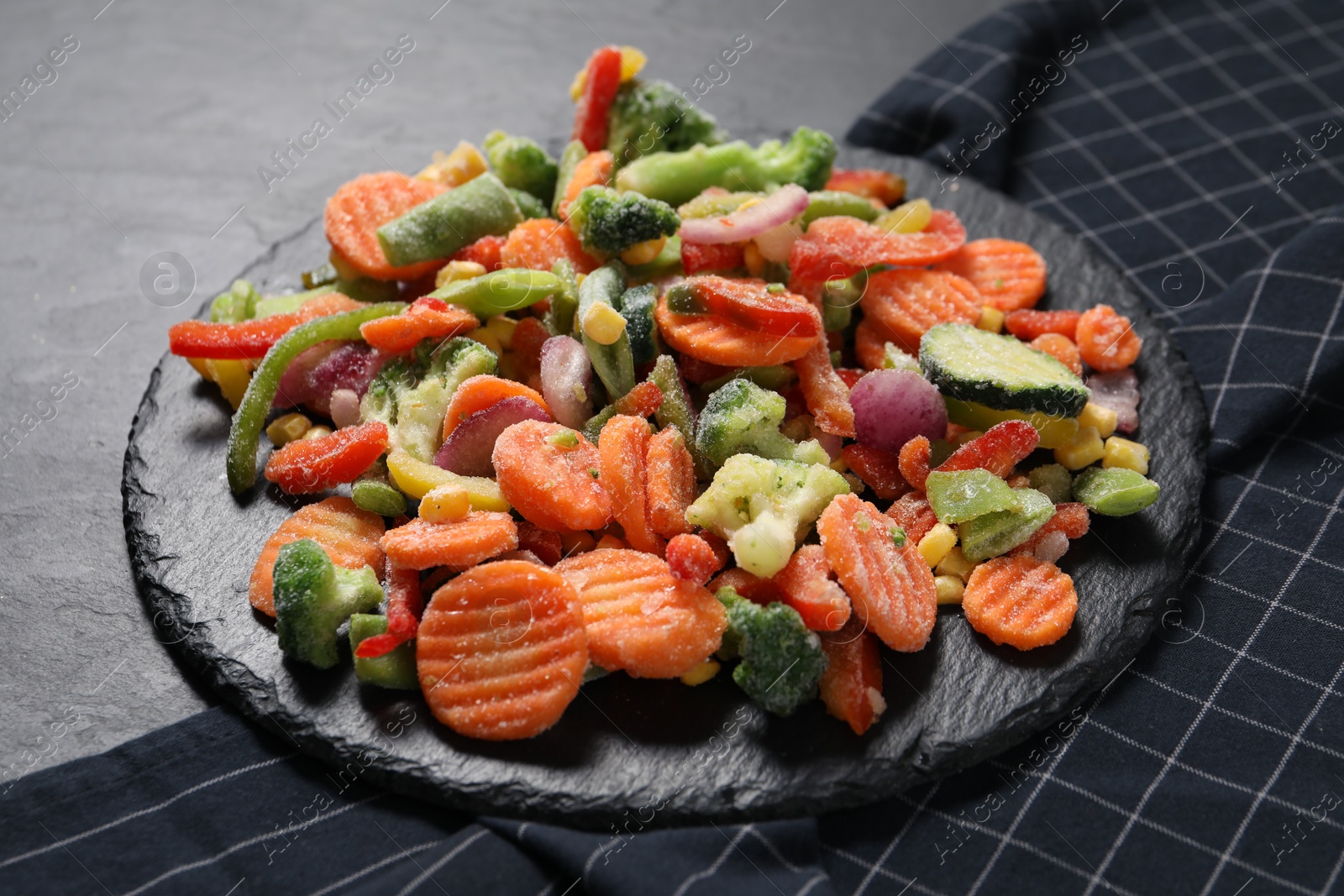 Photo of Mix of frozen vegetables on black table, closeup