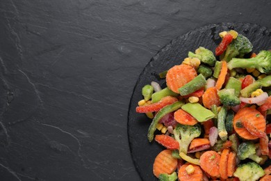 Photo of Mix of frozen vegetables on black table, top view. Space for text