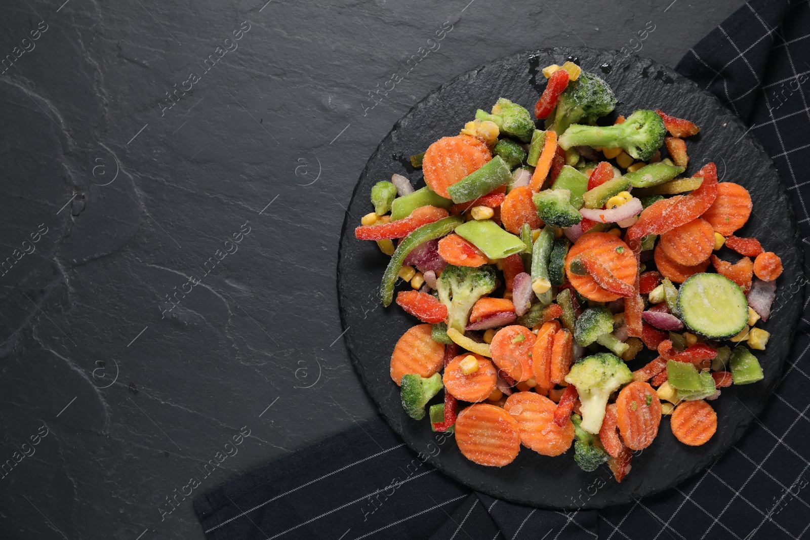 Photo of Mix of frozen vegetables on black table, top view. Space for text