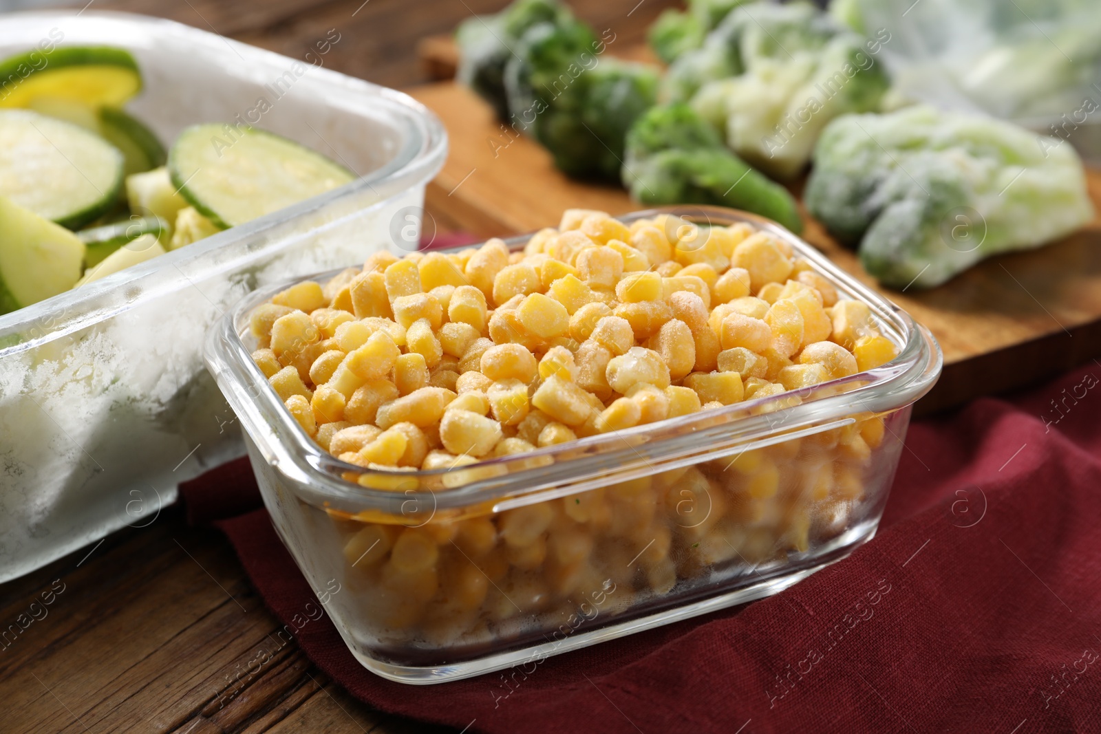 Photo of Frozen corn kernels, zucchini and broccoli on wooden table, closeup