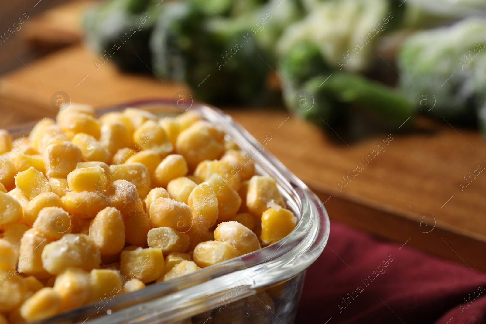 Photo of Frozen corn kernels in glass container on table, closeup