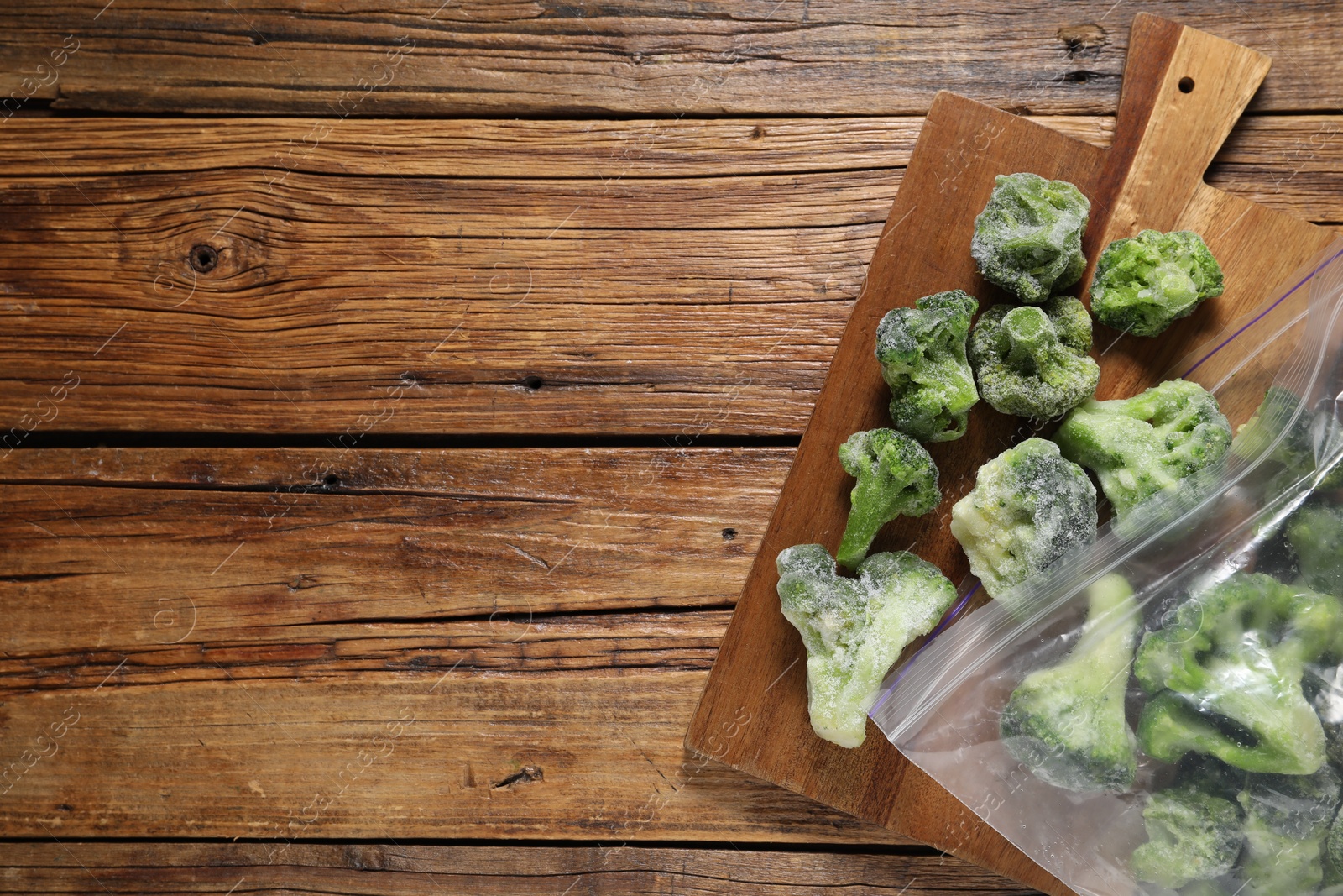 Photo of Frozen broccoli out of plastic bag on wooden table, top view. Space for text