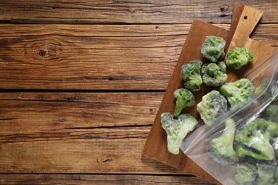 Photo of Frozen broccoli out of plastic bag on wooden table, top view. Space for text