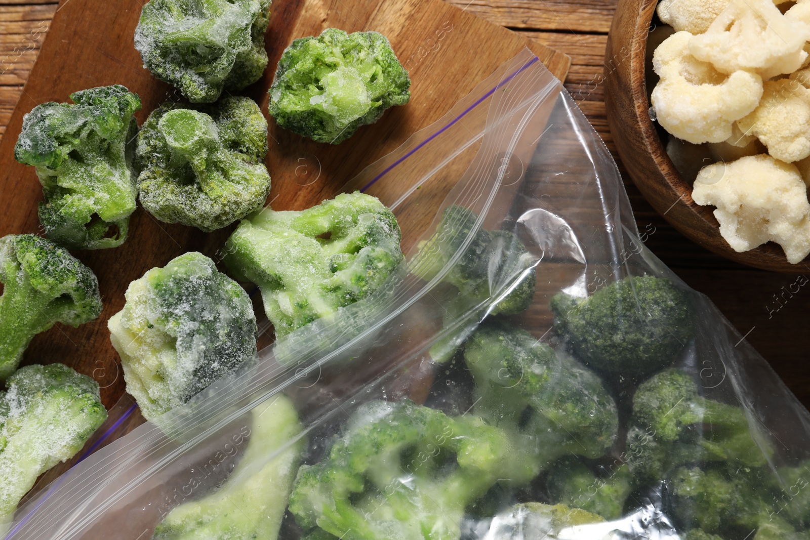 Photo of Frozen broccoli and cauliflower on wooden table, top view