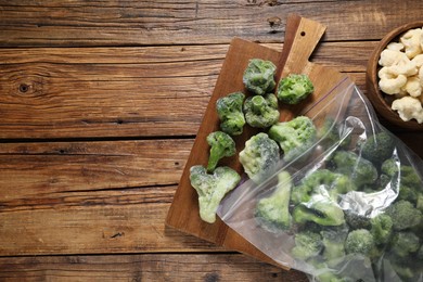 Photo of Frozen broccoli and cauliflower on wooden table, top view. Space for text