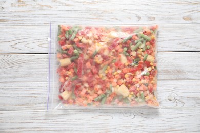 Photo of Mix of frozen vegetables in plastic bag on wooden table, top view