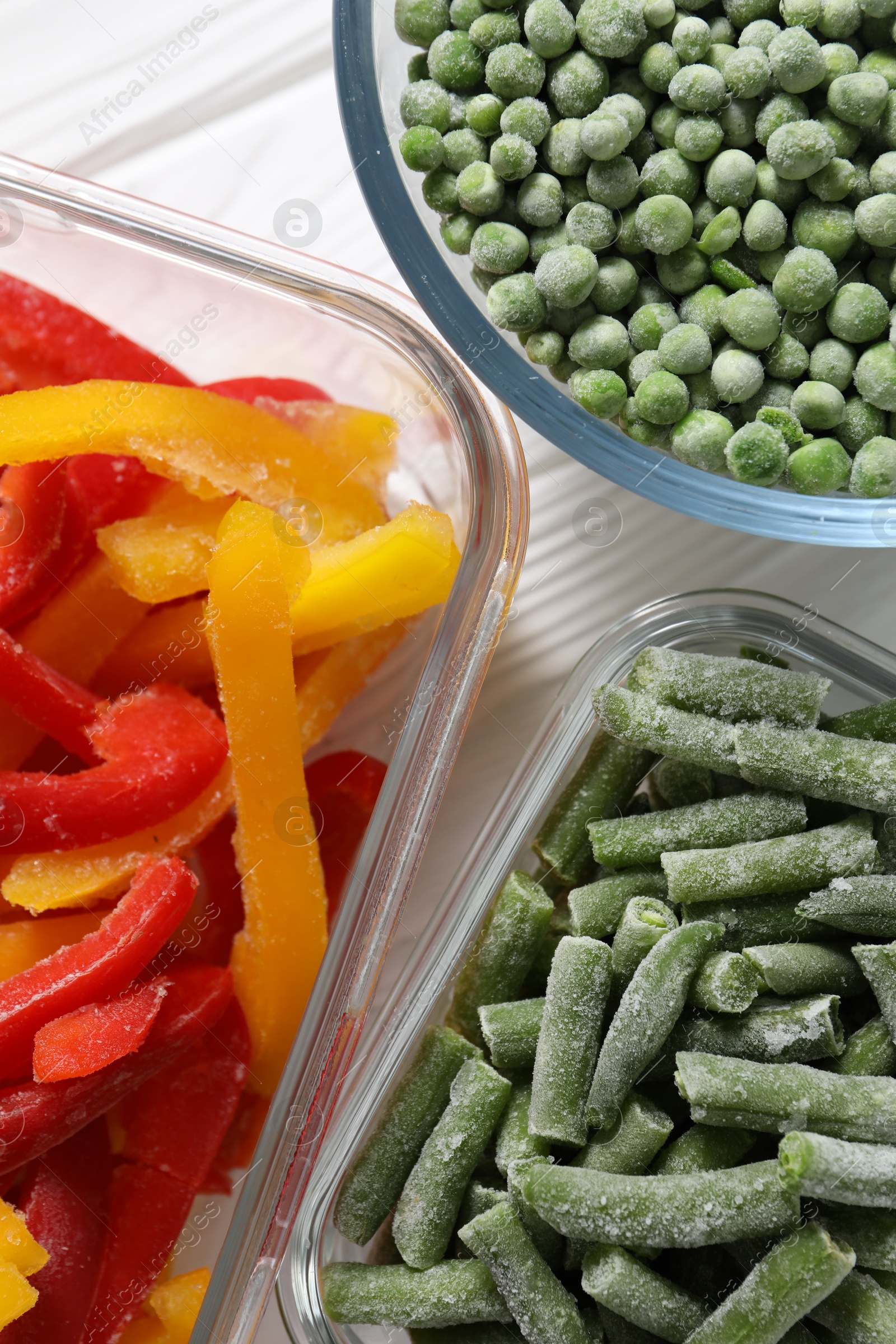 Photo of Frozen green beans, peas and bell peppers on white wooden table, top view