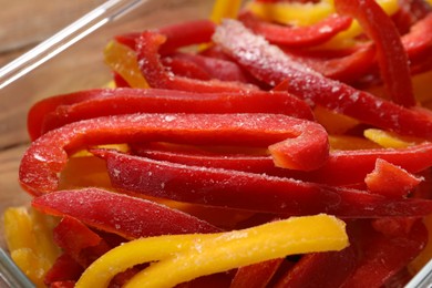 Photo of Slices of frozen bell peppers in glass container on table, closeup