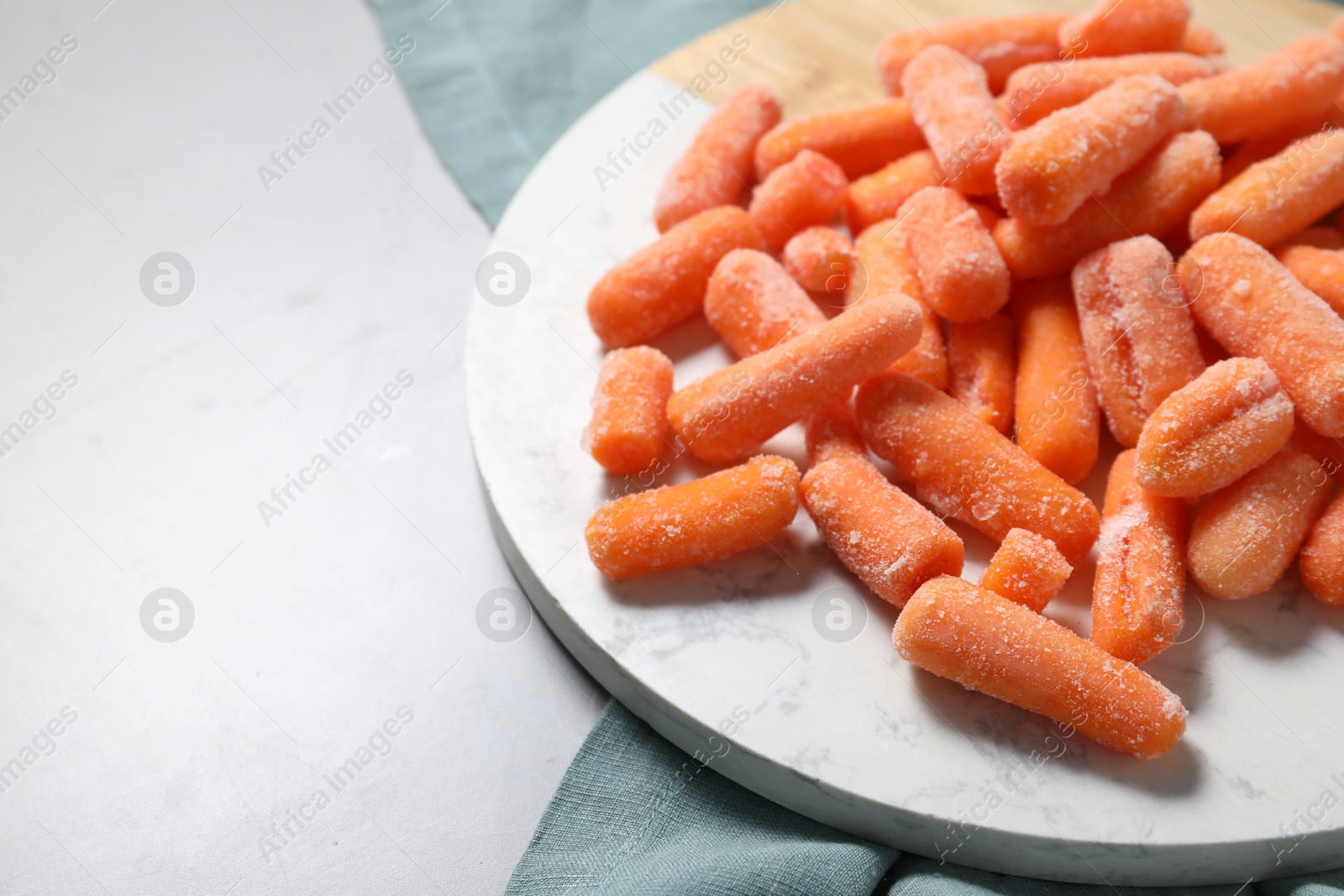 Photo of Frozen baby carrots on grey table, closeup. Space for text