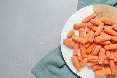 Photo of Frozen baby carrots on grey table, top view. Space for text