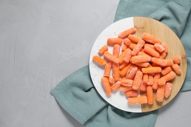 Photo of Frozen baby carrots on grey table, top view. Space for text