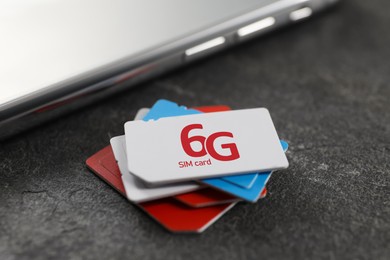 Image of 6G SIM cards and mobile phone on black table, closeup