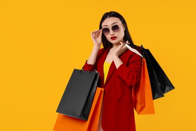 Beautiful woman with shopping bags on golden background