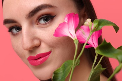 Image of Beautiful woman with flowers on coral color background, closeup