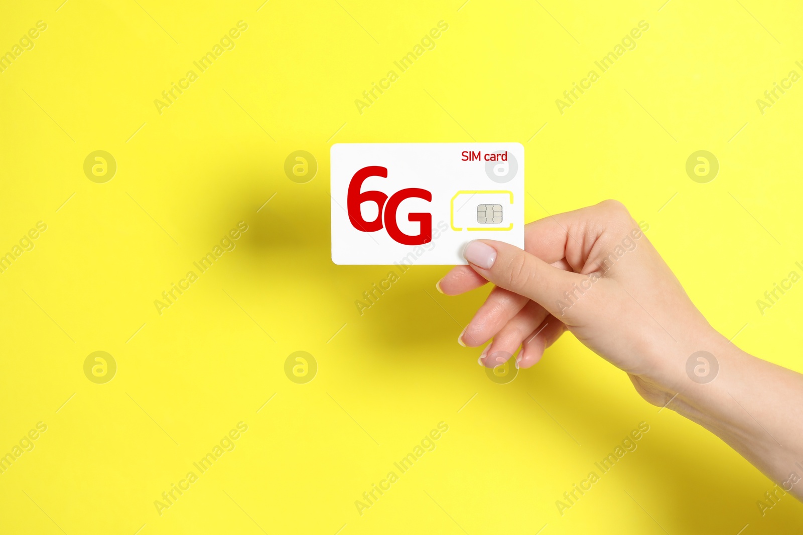 Image of Woman holding 6G SIM card on yellow background, closeup. Space for text