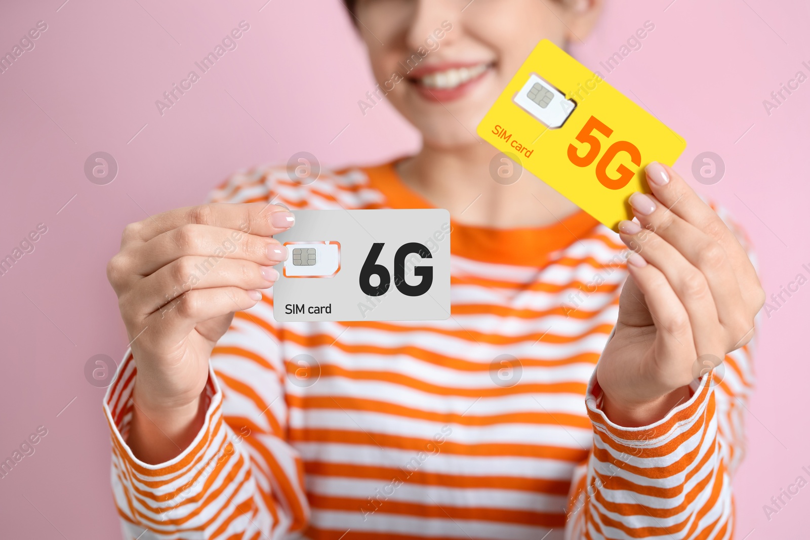 Image of Woman holding 5G and 6G SIM cards on pink background, closeup