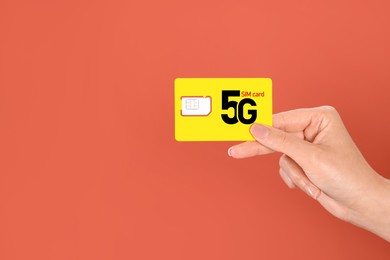 Woman holding 5G SIM card on terracotta background, closeup. Space for text