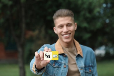 Happy man with 5G SIM card outdoors, selective focus