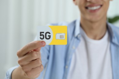 Man holding 5G SIM card indoors, closeup view