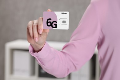 Image of Woman holding 6G SIM card indoors, closeup view