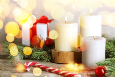 Image of Christmas composition with burning candles on wooden table, bokeh effect. Festive card