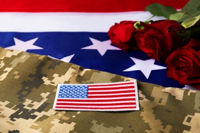 Photo of Veterans day. USA army patch, rose flowers and military uniform on American flag, closeup