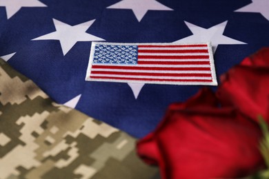 Photo of Veterans day. USA army patch, rose flowers and military uniform on American flag, closeup