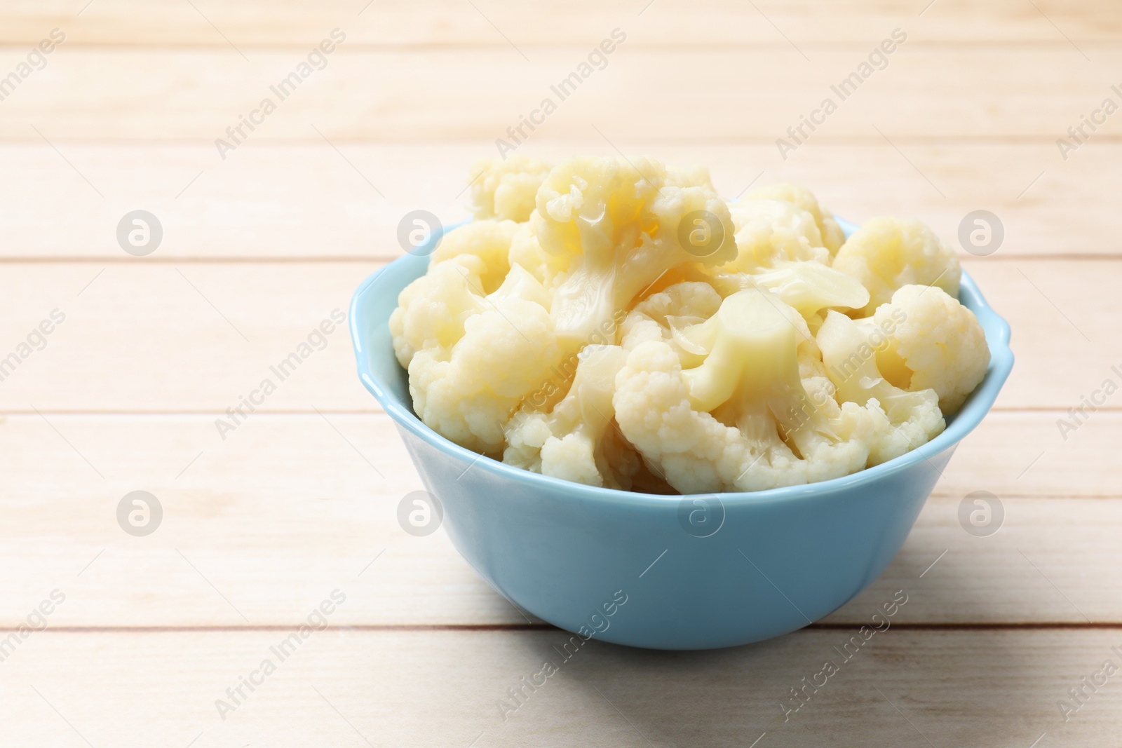 Photo of Tasty cooked cauliflower on white wooden table, closeup. Space for text