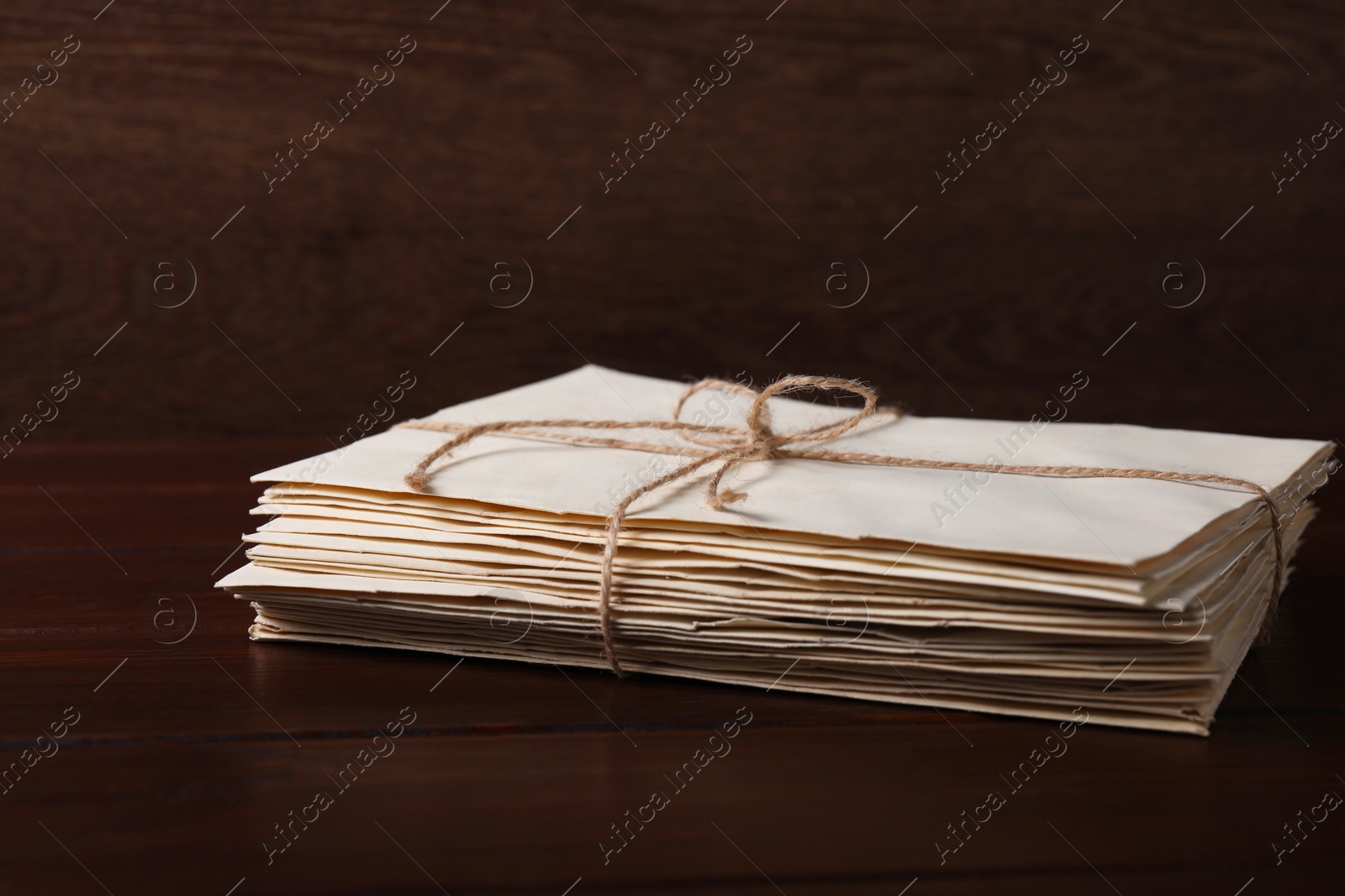 Photo of Stack of old letters tied with twine on wooden table, closeup