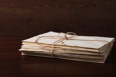 Photo of Stack of old letters tied with twine on wooden table, closeup