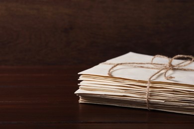 Photo of Stack of old letters tied with twine on wooden table, closeup. Space for text