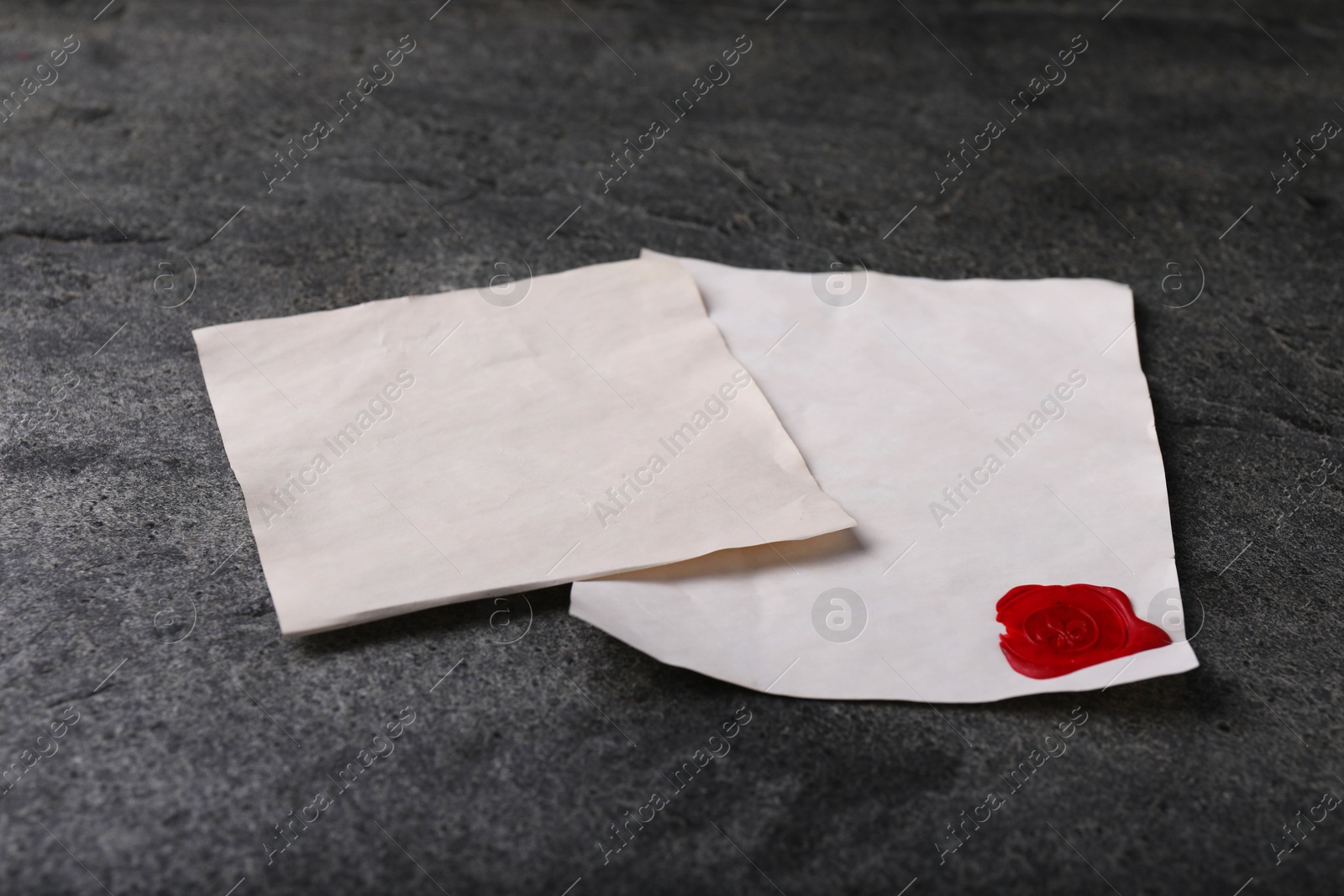 Photo of Old letters with wax stamp on grey table, closeup